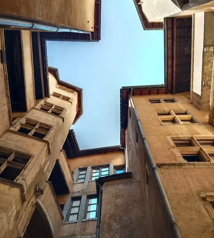Cour intérieure d'une traboule de la Croix-Rousse : rectangle de ciel bleu encadré par les façades en pierre ocre