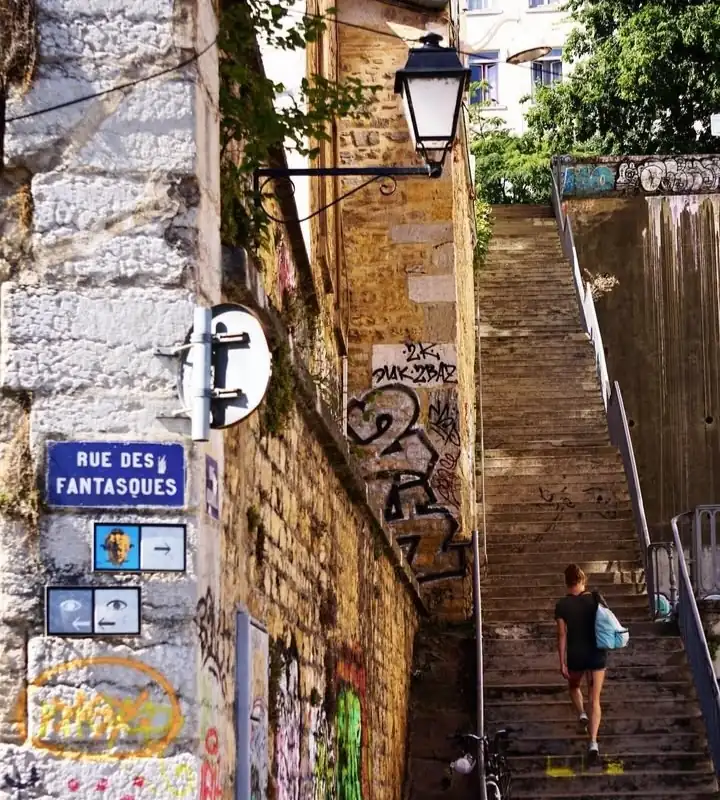 Rue des Fantasques dans les pentes de la Croix-Rousse : escaliers en bois et murs patinés ornés de graffitis