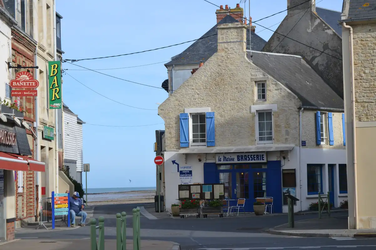 La brasserie La Marine aux volets bleus à Colleville-sur-Mer, la mer entrevue au bout de la rue