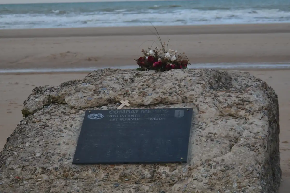 Stèle commémorative des Combat Medics sur le sable d'Omaha Beach, bouquet de fleurs déposé dessus