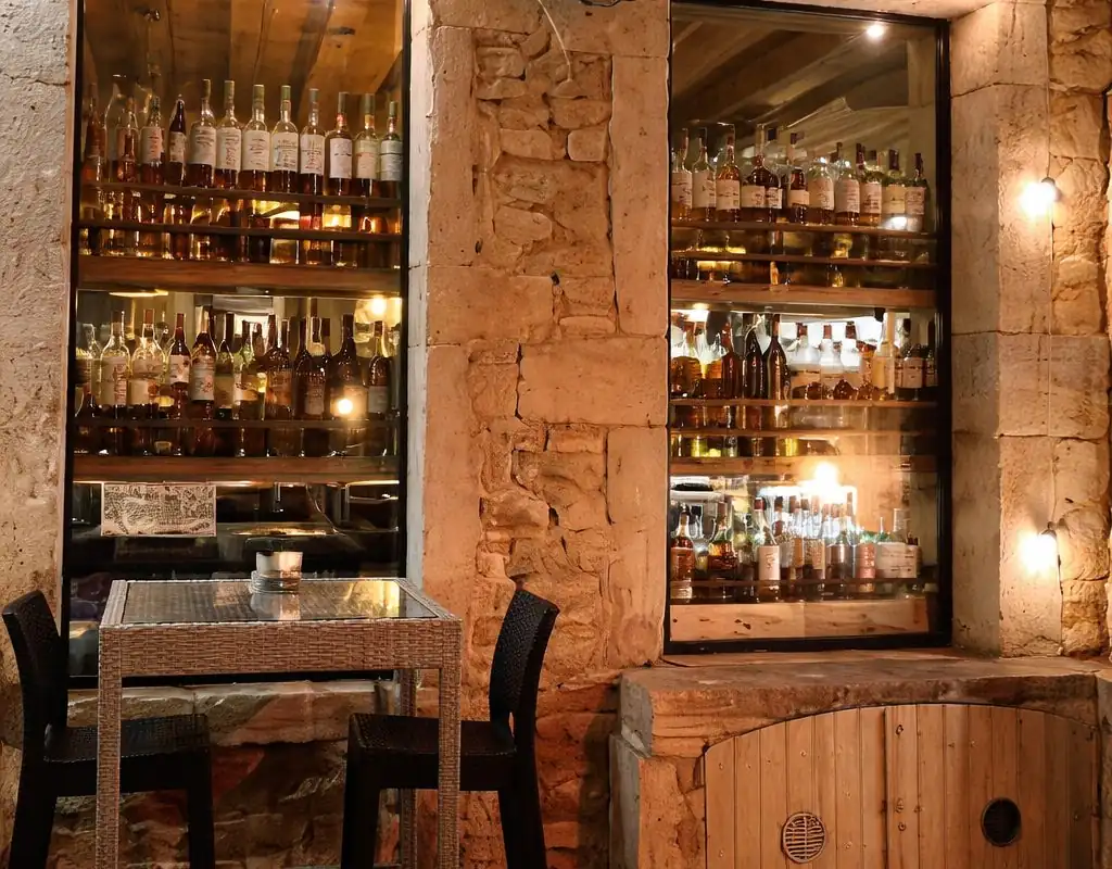 Terrasse extérieure du Bout du Monde avec tables et chaises devant les vitrines illuminées du bar à vins