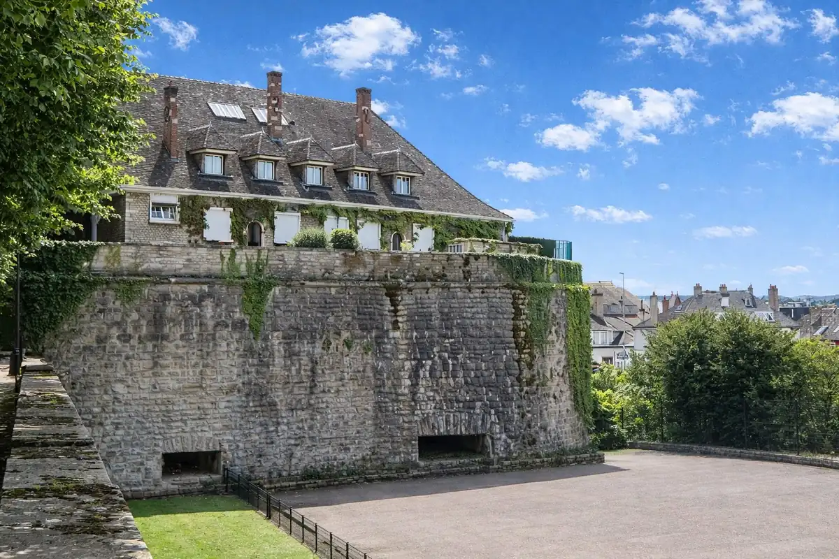Remparts médiévaux de Beaune couverts de lierre avec vue sur les toits de la vieille ville