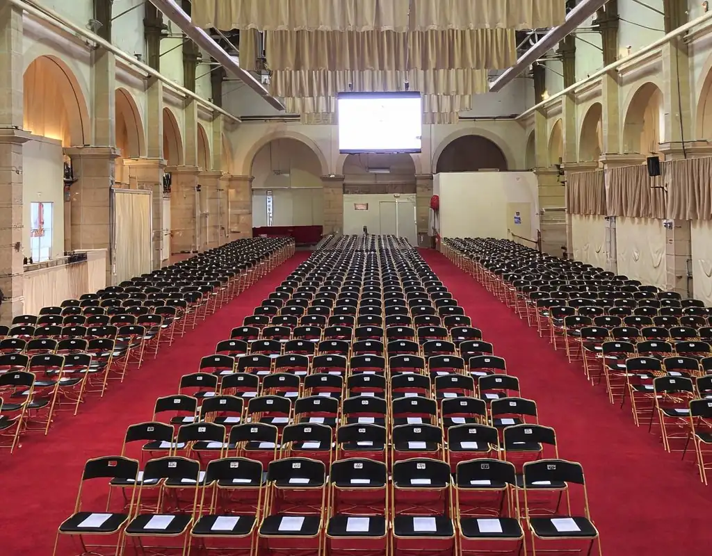 Grande salle de vente aux enchères des Hospices de Beaune : rangées de chaises noires sur moquette rouge dans un espace monumental